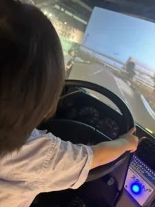 運転シミュレーターのハンドルを握る3歳の息子