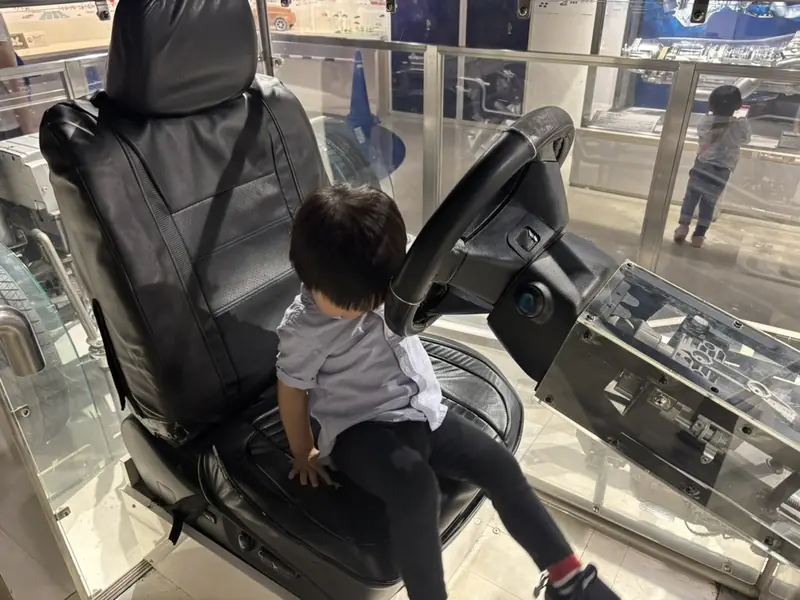 スケルトンの車の運転席に座る息子